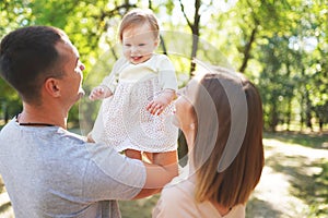 Happy young family spending time together, mother and father with baby outside in green nature