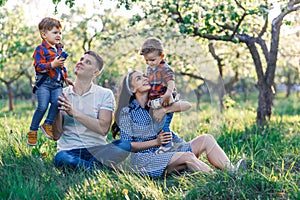 Happy young family spending time together outside in green nature. Parents playing with twins outside.