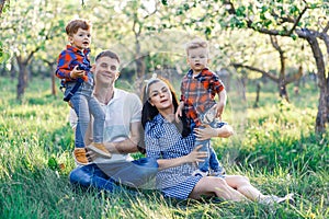 Happy young family spending time together outside in green nature. Parents playing with twins outside.