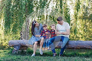 Happy young family spending time together outside in green nature. Parents playing with twins outside.