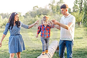 Happy young family spending time together outside in green nature. Parents playing with twins outside.