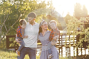 Happy young family spending time together outside in green nature. Parents playing with twins outside.