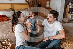 A happy young family spends time together in a home interior. A beautiful happy family spending time together at home.