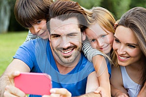 Happy young family taking selfies with her smartphone in the par