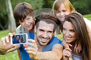 Happy young family taking selfies with her smartphone in the par