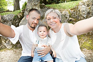 Happy young family taking selfies with her smartphone in the park