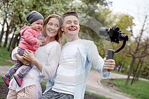 Happy young family taking video selfies with her camera on the gimbal steadycam photo