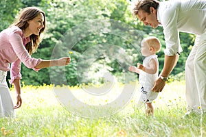 Happy young family teaching baby to walk