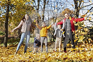 Happy young family with three children in the autumn park. Love and tenderness. Walk in the golden season