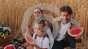 Happy Young Family Of Three Eating Watermelon While Having Picnic In Wheat Field