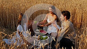 Happy young family of three having picnic in wheat field together.