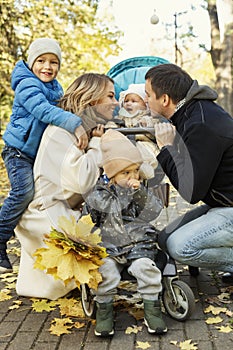 Happy young family with three small children in a beautiful autumn park are walking and hugging. Love, tenderness and