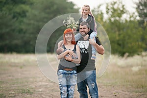 Happy young family with two children on walk in park.