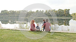 Happy young family with two sons walks and rests in a park by the river. Family and relationship concept