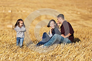 Happy young family with two year girl in harvested field