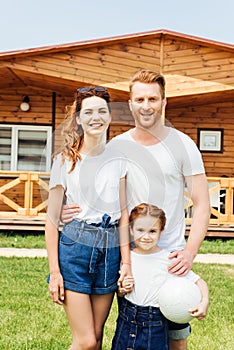 happy young family with volleyball ball standing in front of