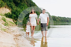 Happy young family are walking near the lake, mom dad and daughter playing outdoors. summer holiday, Mother`s, father`s, baby`s