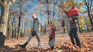 A happy young family walks in the foliage of a city park.