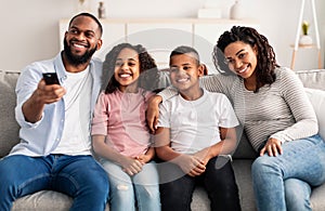 Happy young family watching television sitting on sofa