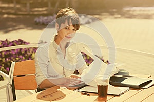 Happy young fashion business woman working at sidewalk cafe