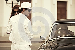 Happy young fashion couple in love next to retro car