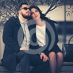 Happy young fashion couple in love sitting on bench