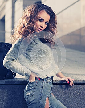 Happy young fashion woman in blue pullover and ripped jeans