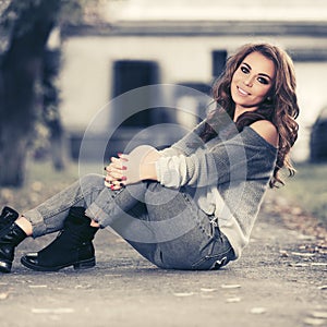 Happy young fashion woman in blue pullover and ripped jeans