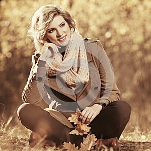 Happy young fashion woman in classic beige coat in autumn park