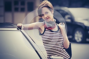 Happy young fashion woman with pixie hair leaning on her car