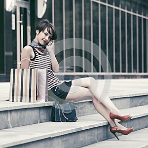 Happy young fashion woman with shopping bags talking on cell phone