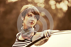 Happy young fashion woman in tank top next to her car