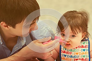 Happy young father feeding baby girl