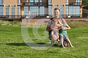 Happy young father holding two sons in the park