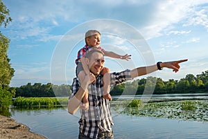 Happy young father holds his son piggyback ride on his shoulders