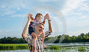 Happy young father holds his son piggyback ride on his shoulders