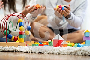 Happy young father and mother and a little daughter playing with Toy wooden blocks