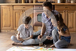 Happy young father painting with little children.