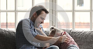 Happy young father parent tickling small laughing kid daughter.