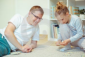 Happy young father playing with his cute little daughter at home