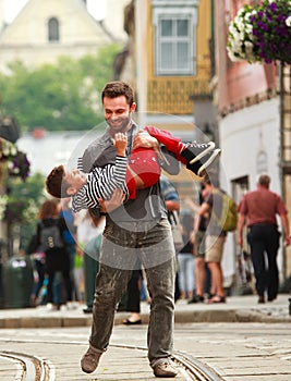 Happy young father playing with his son on background of city