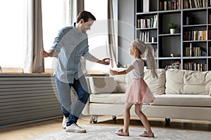 Happy young father showing inviting dancing moves to smiling daughter. photo