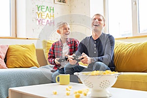 Happy young father and son boy 8 years old play together in a game console, fun and entertainment for the family