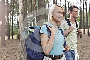 Happy young female backpacker with man hiking in woods