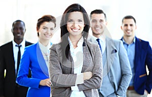 Happy young female business leader standing in front of her team