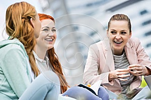 Happy young female college friends studying outdoors