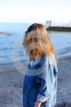 Happy young female develops hair and poses on camera, standing o