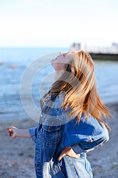 Happy young female develops hair and poses on camera, standing o