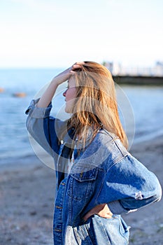 Happy young female develops hair and poses on camera, standing o