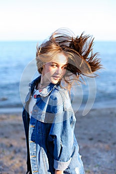 Happy young female develops hair and poses on camera, standing o